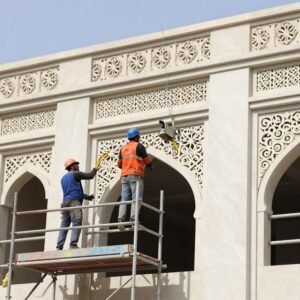 عمال يقومون بترميم واجهة مبنى في الكويت باستخدام مواد حديثة